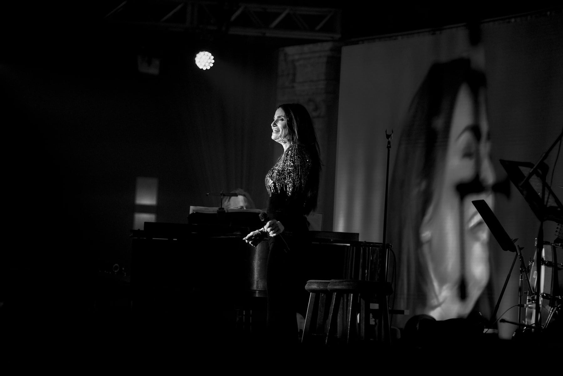 Black-and-white event photograph of Idina Menzel between songs at a corporate performance