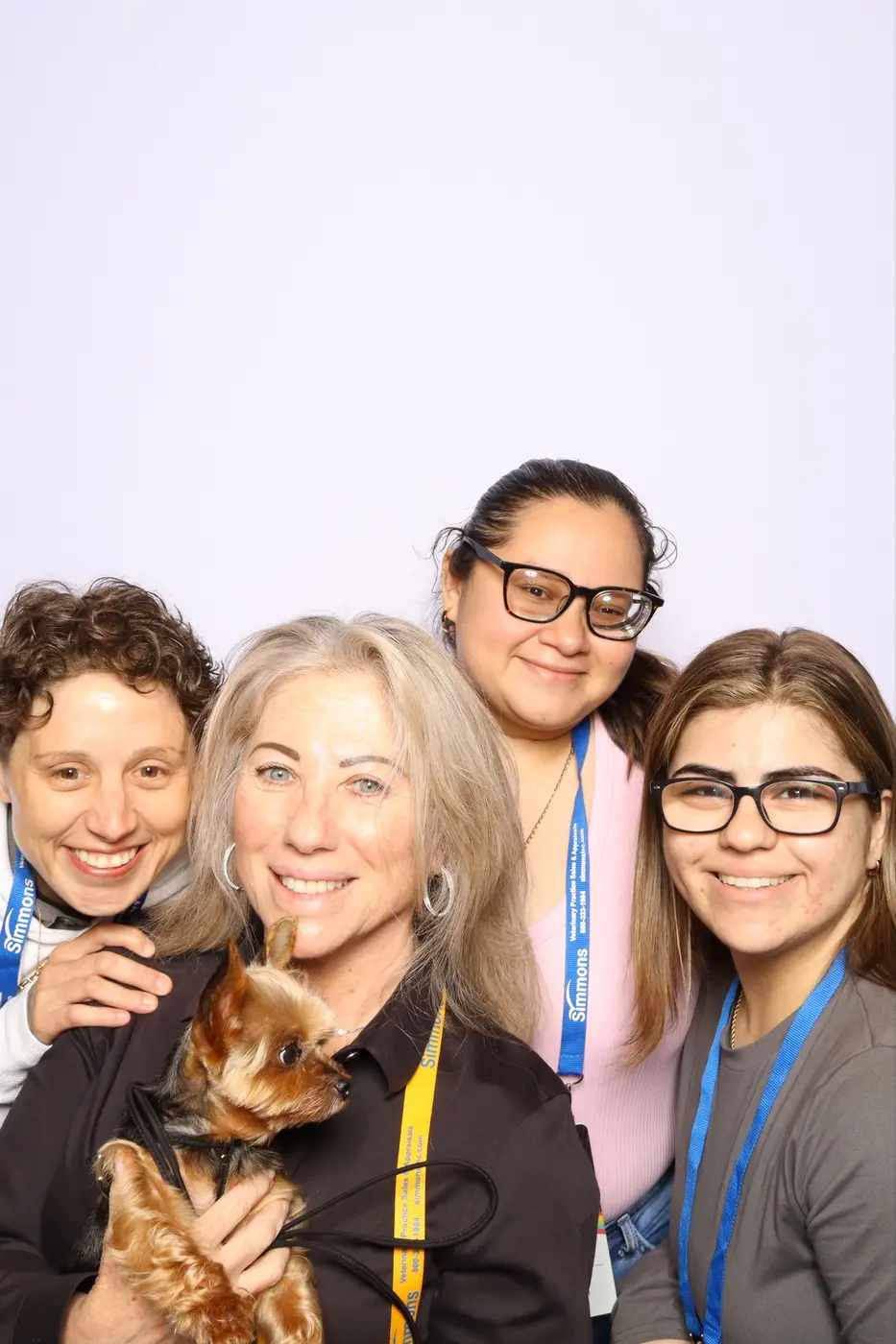 Three veterinary conference attendees posing with a small dog