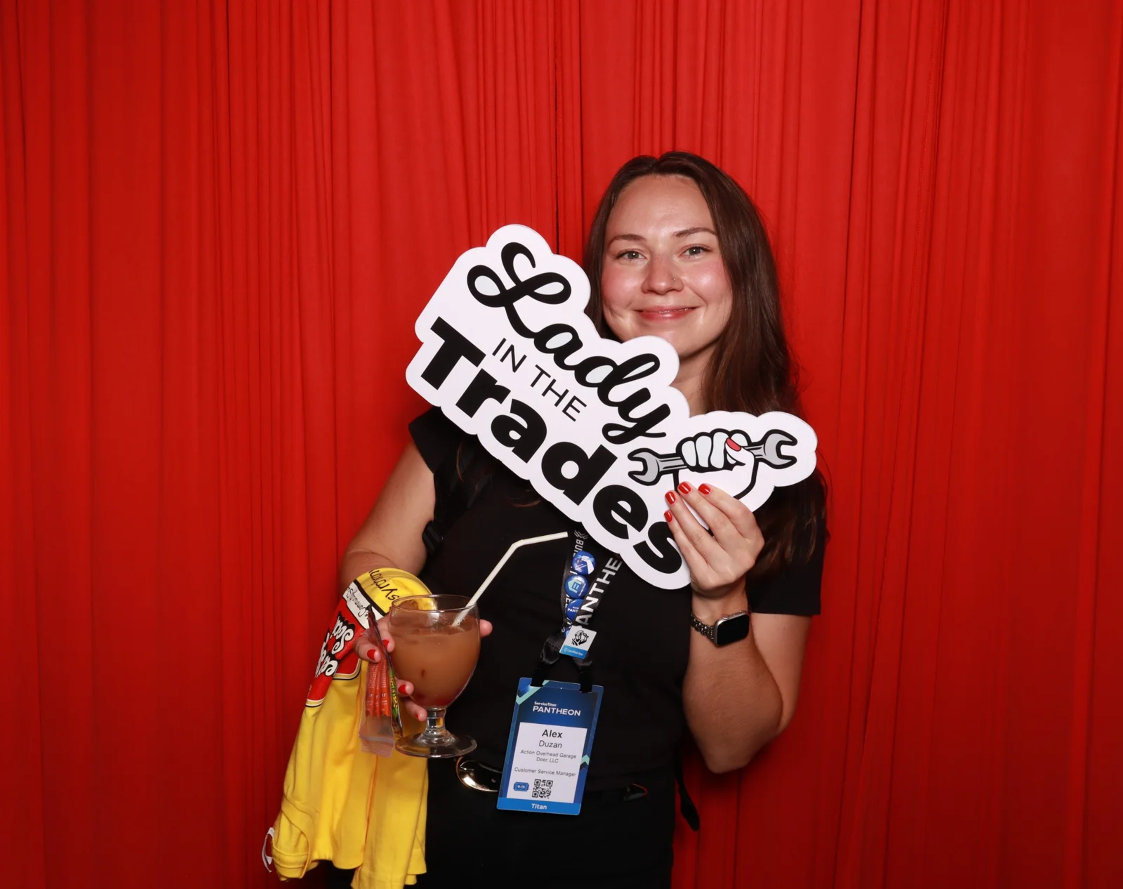 Lady Titans guest holding a Lady Titans in the Trades prop at the DSLR photo booth