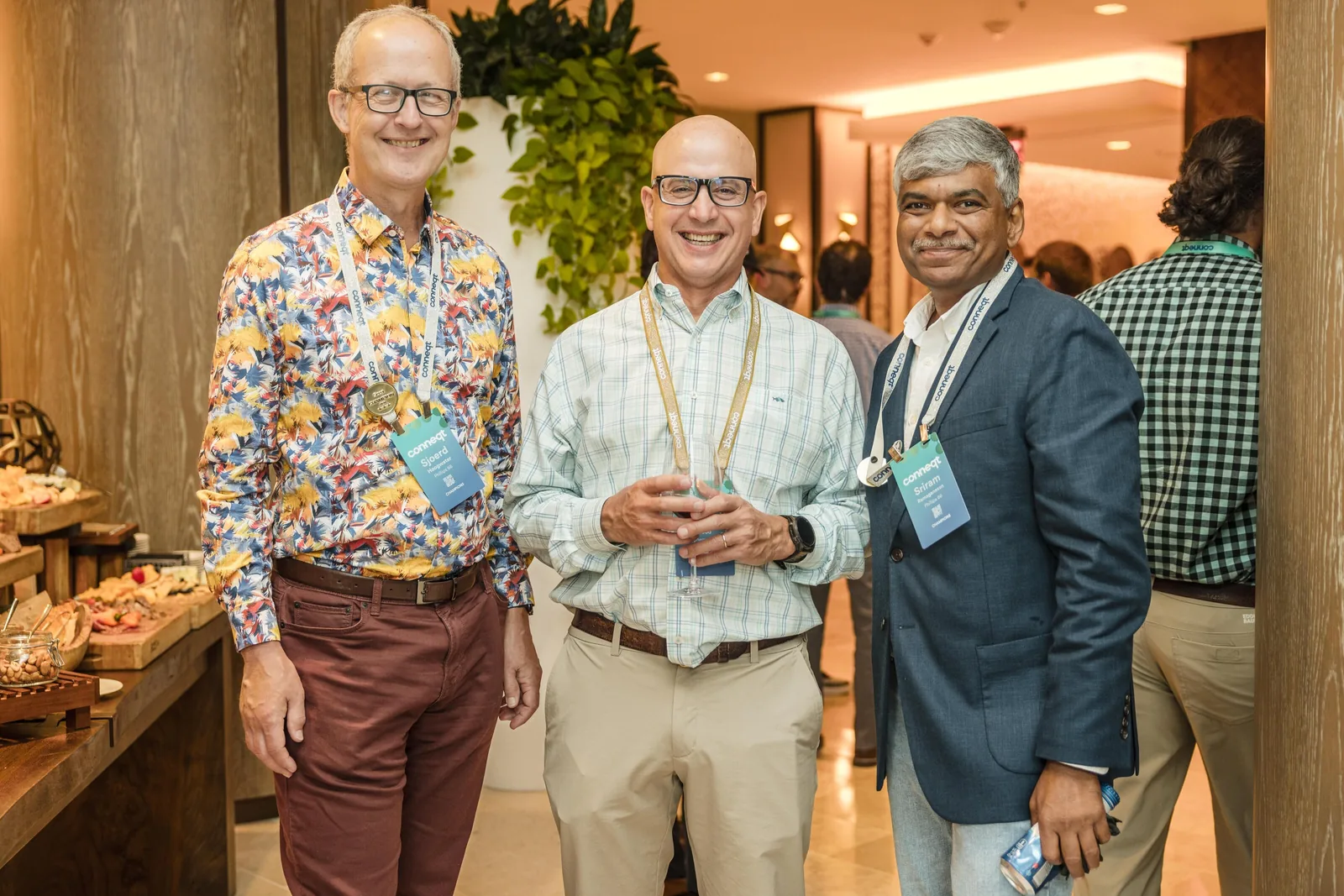 Roaming photograph of three corporate guests with conference lanyards at a networking reception